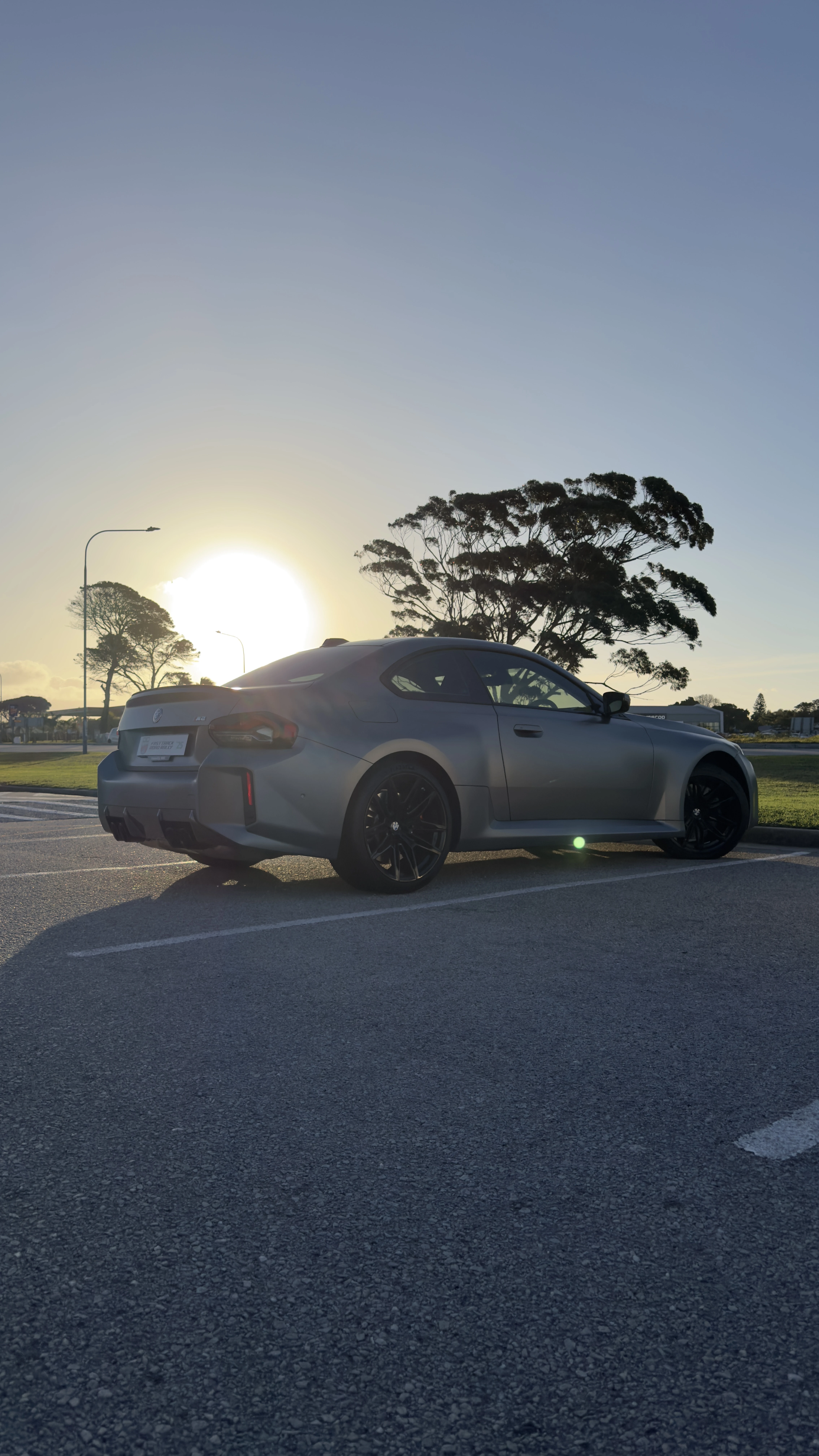 Silver BMW M2 G87 rear three-quarter at sunset